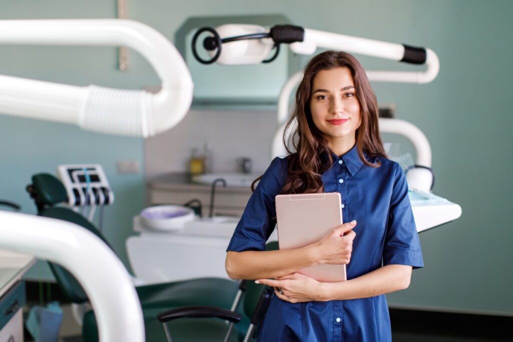 aluna do curso de odontologia 4 anos segurando um tablet na sala em frente a cadeira de dentista